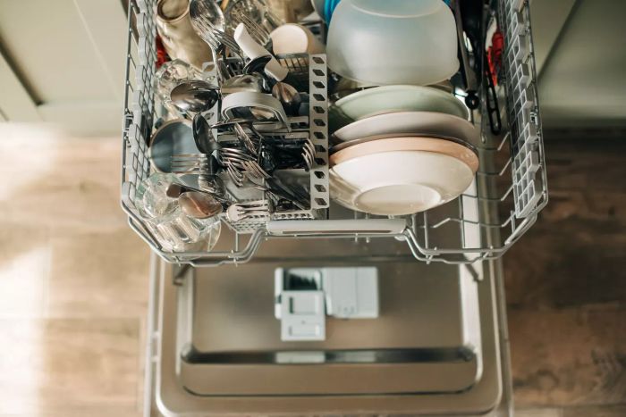 Dishwasher door opened, revealing clean dishes in a bright white kitchen