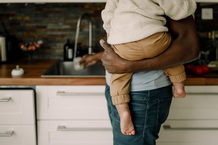 A person holding a baby in a kitchen.