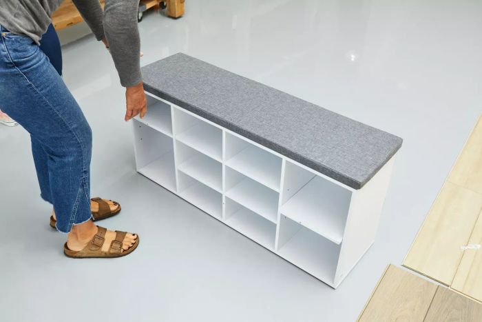 A person with the fully assembled VASAGLE Shoe Bench placed on a grey floor