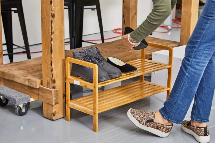 A person organizing shoes on the Rebrilliant 2-Tier 8-Pair Shoe Rack