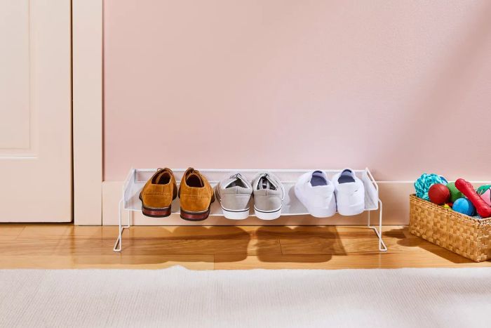 The Container Store White Mesh Stackable Shoe Shelf placed on a wooden floor with shoes neatly arranged