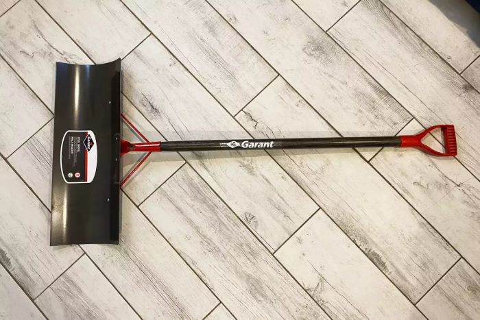 The Garant NSP24D Nordic 24-Inch Steel Blade Snow Pusher showcased on a wooden floor