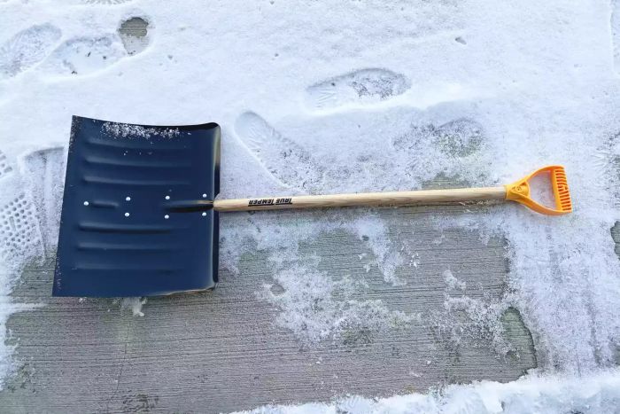 True Temper 18-Inch Steel Snow Shovel resting on the cement floor, partially covered with snow