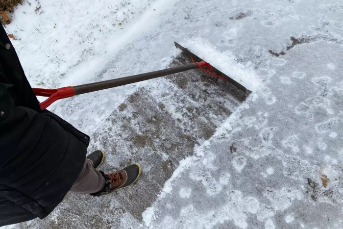 Person using the Garant NSP24D Nordic 24-Inch Steel Blade Snow Pusher to clear snow from a surface
