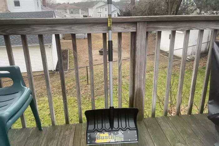 Yeoman BustR Snow Shovel resting against a wooden railing