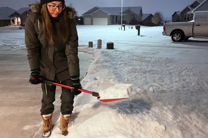A person using the BirdRock 34-inch Folding Emergency Snow Shovel to clear snow