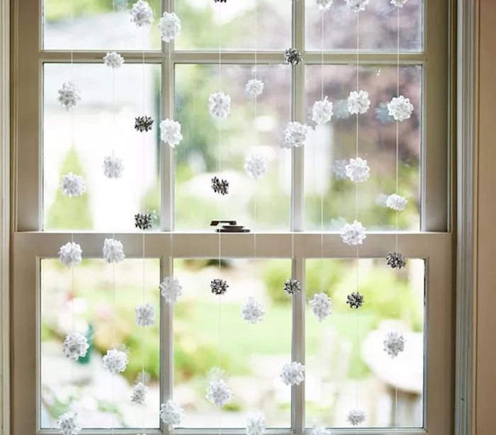 Ideas for Christmas decorations, silver and white gift bows suspended in a window.