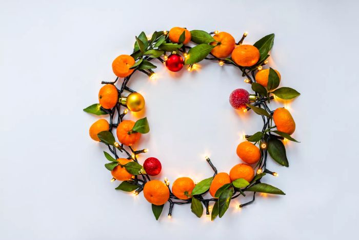 A festive Christmas wreath adorned with tangerines and a shimmering garland of lights.