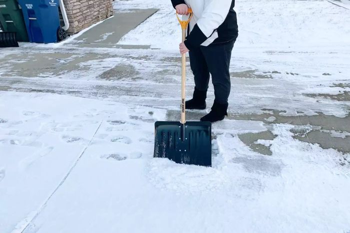 A person is seen clearing snow from the entryway road with the True Temper 18-Inch Steel Snow Shovel.