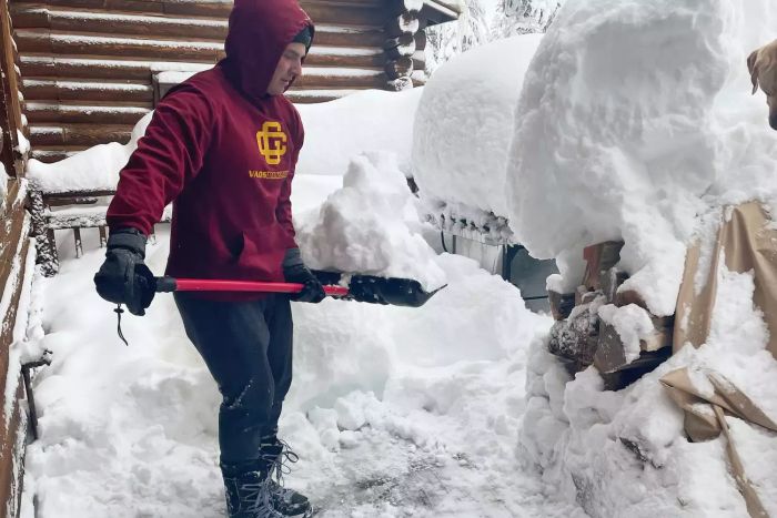 A person clearing snow using the Bully Tools 27-Inch Fiberglass D-Grip Handle Snow Pusher