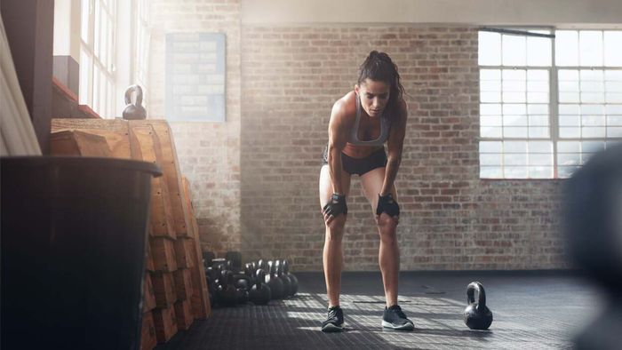 a fatigued woman sitting beside a kettlebell