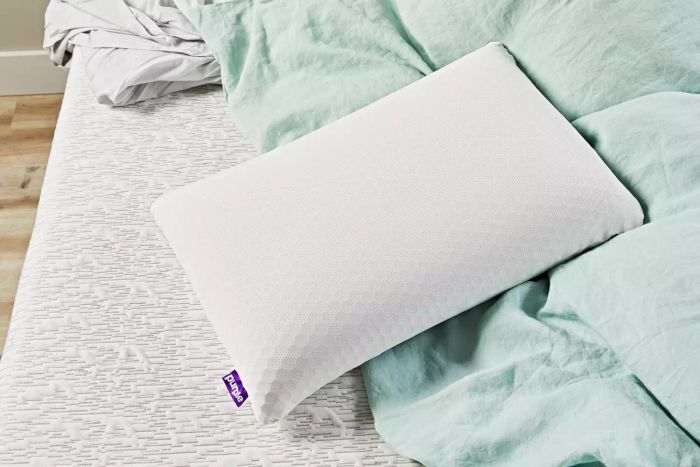 The Purple Harmony Pillow resting on a bed with a green comforter