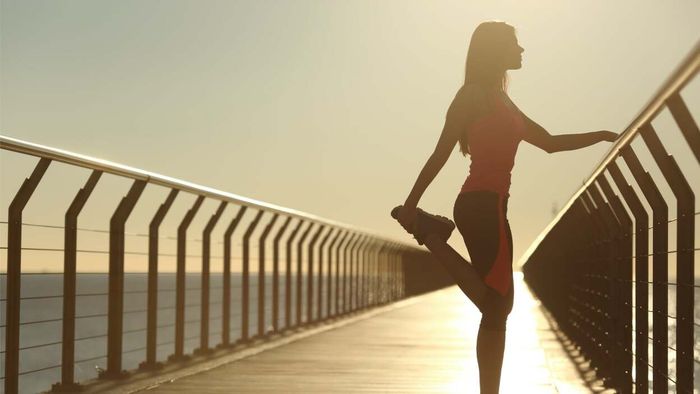 runner stretching by a railing on a hot day