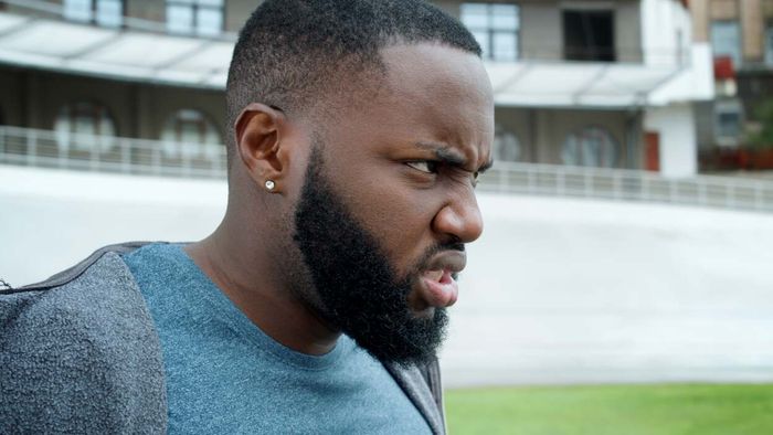 A young man showing a frustrated expression while outdoors