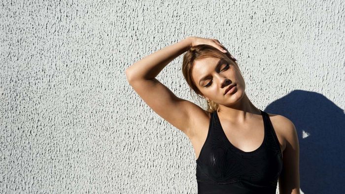 woman performing a neck stretch by gently pressing her hand against her head