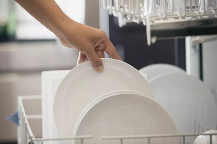 A woman loading dishes into a dishwasher