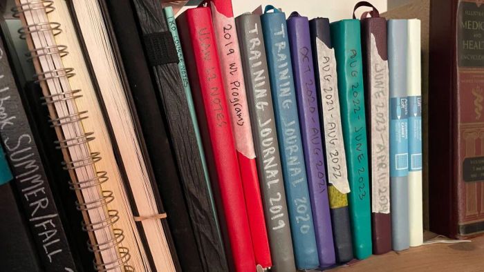 Training journals stacked on a shelf, each marked with the date
