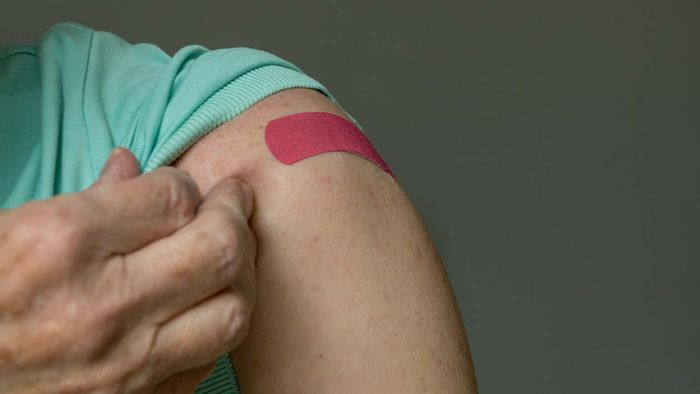 An elderly individual's arm displaying a band-aid