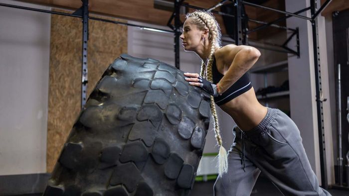 A woman flipping a tire in the gym