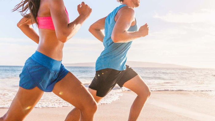 A man and a woman jogging along the shore