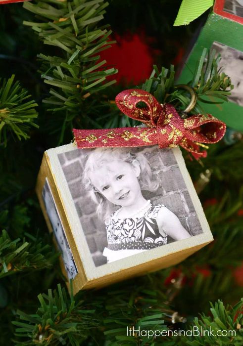 A photo block ornament hanging on a Christmas tree.