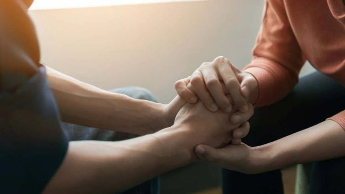 individuals supporting each other, holding hands in comfort