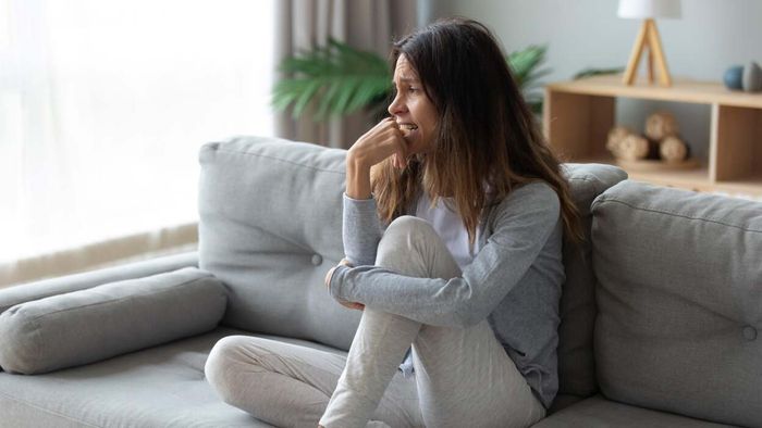 A woman sits on a couch, feeling down