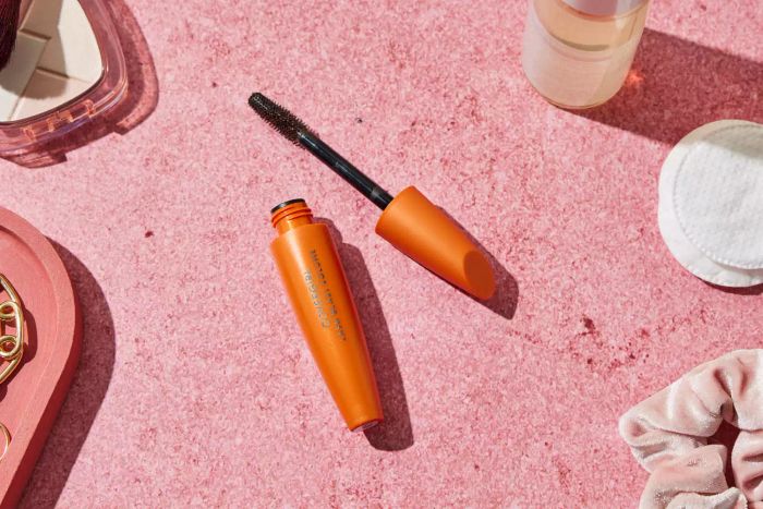 An open tube of CoverGirl LashBlast Volume Waterproof Mascara resting on a soft pink backdrop