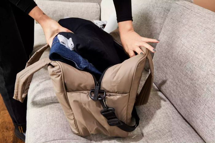 Hands packing clothes into the Calpak Luka Duffel Bag