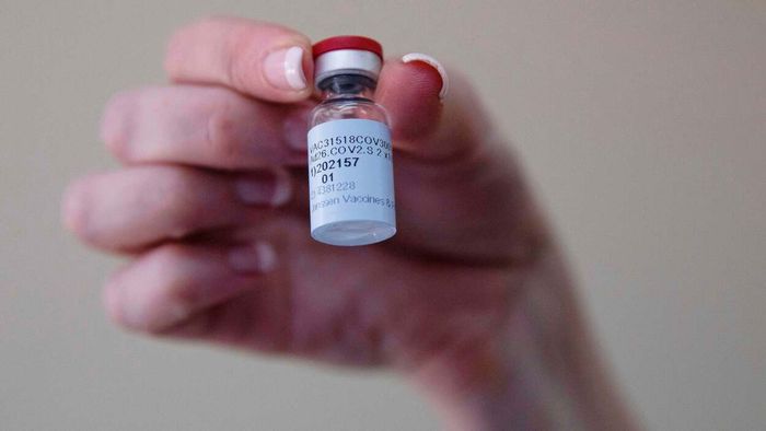 a hand gripping a vial containing a vaccine