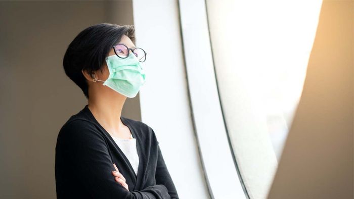 woman in a mask gazing out the window