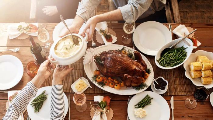 A beautifully set Thanksgiving dinner table, complete with turkey, corn on the cob, green beans, and mashed potatoes