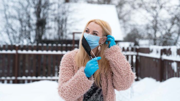 A woman layering a second mask over her first