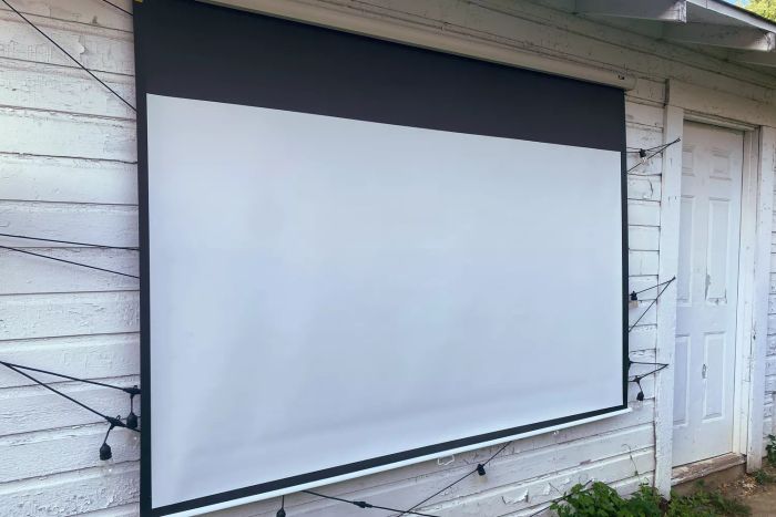 A close-up view of the Elite Screens Manual B Pull-Down Projection Screen mounted on a wall.