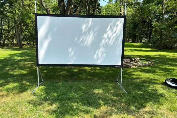 The Elite Screens Yard Master Plus Projection Screen set up for an outdoor movie viewing in a backyard