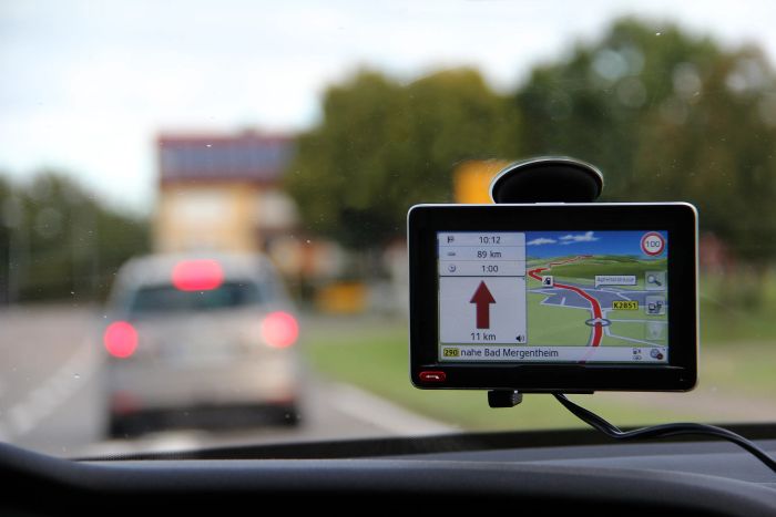 A car GPS screen shows navigation details and the distance to 'Bad Mergentheim.' A vehicle is visible ahead on the road