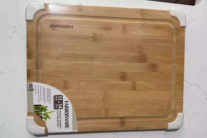 The Farberware Nonslip Bamboo Cutting Board with Juice Groove in its plastic packaging before use