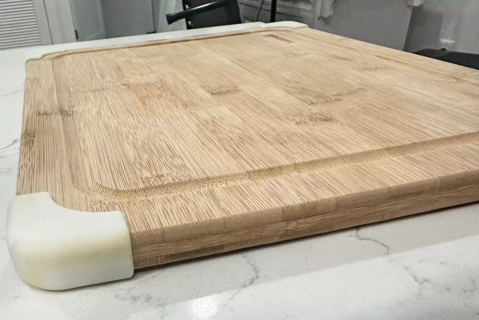 The Farberware Nonslip Bamboo Cutting Board with Juice Groove placed on a white countertop