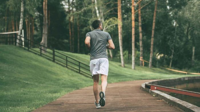 A runner is seen from behind on what appears to be a park trail.