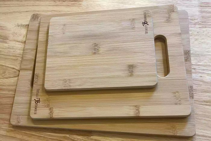 The Totally Bamboo 3-Piece Bamboo Cutting Board Set stacked neatly on a wooden table