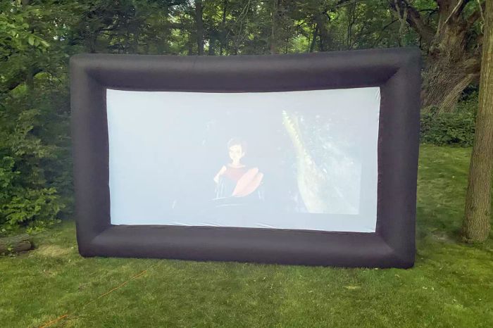 The Holiday Styling 19-Foot Giant Inflatable Outdoor Projector Screen set up in a spacious backyard