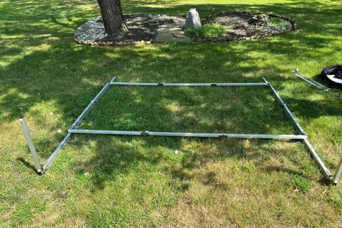 The frame of an Elite Screens Yard Master Plus Projection Screen resting on the grass