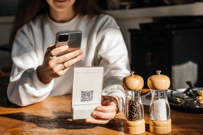 A person scanning a QR code on their smartphone next to salt and pepper shakers on a wooden table