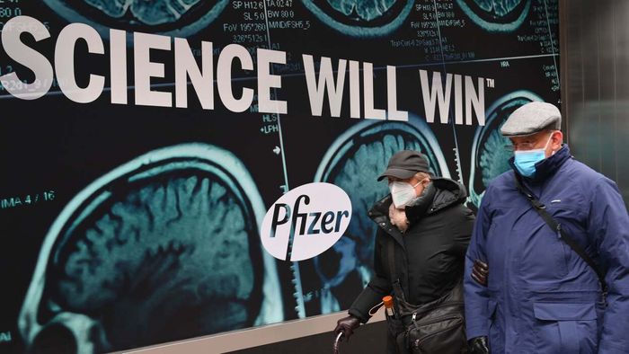 masked individuals standing before a massive Pfizer billboard proclaiming 'SCIENCE WILL WIN'