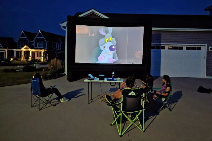 A group of people enjoying a movie on the XHYCPY 20 Feet Inflatable Outdoor Movie Projector Screen