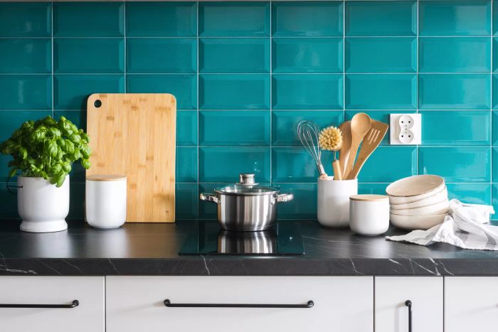 A detailed kitchen scene featuring a cozy interior, white cabinets with metallic handles, a cooking pot on an electric stove, ceramic storage jars, and neatly arranged bowls on a dark countertop