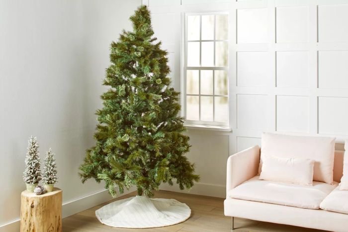 A Puleo International 7.5 Pre-Lit Teton Pine Artificial Christmas Tree showcased in the corner of a cozy living room