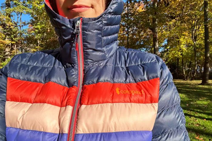 A model is seen wearing the Cotopaxi Women's Fuego Hooded Down Jacket