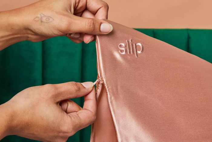 Hands zipping up the Slip Pure Silk Pillowcase