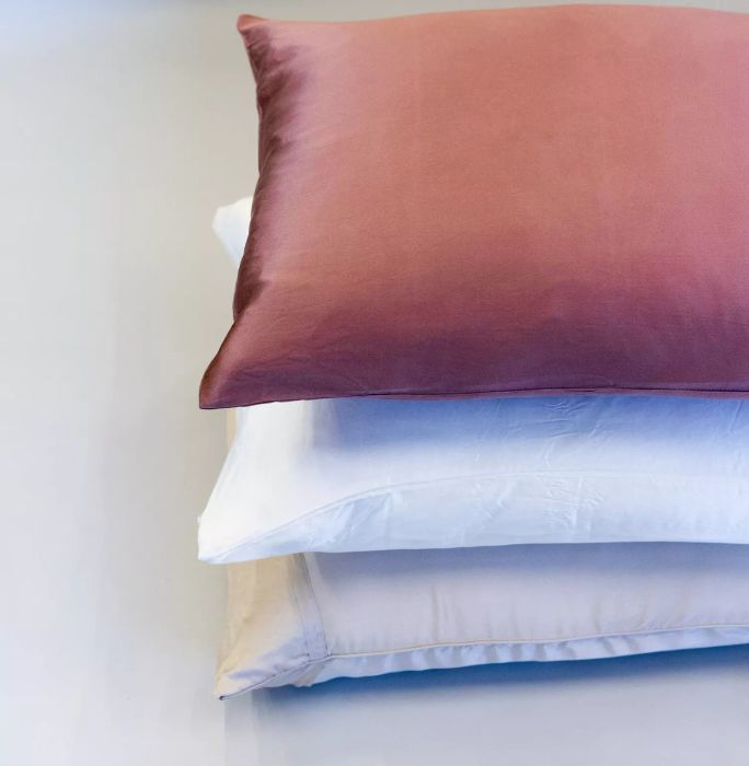 Close-up of three pillows with Silk Pillowcases in various colors, neatly stacked